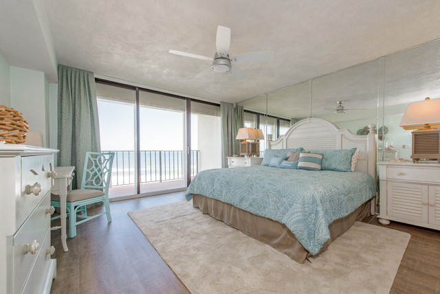A beach style bedroom with a large bed and a view of the ocean.