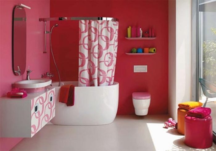 A kids bathroom with pink walls and pink furniture.