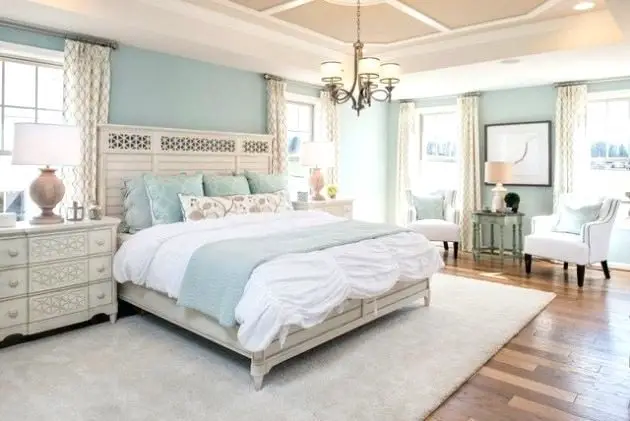 A beach style bedroom with light blue walls and white furniture.
