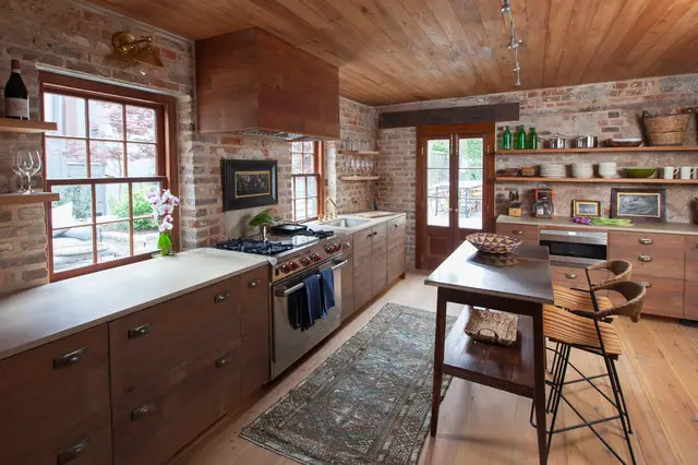 A rustic kitchen with wood floors and brick walls.