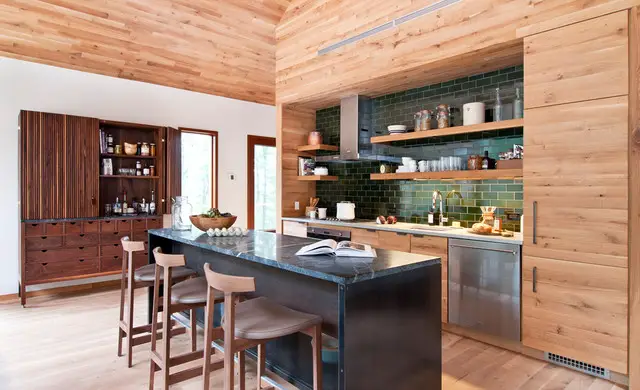 A rustic kitchen with a wooden ceiling and bar stools.
