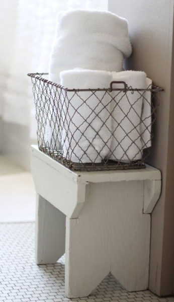 A white basket with towels on it next to bathroom towel storage.