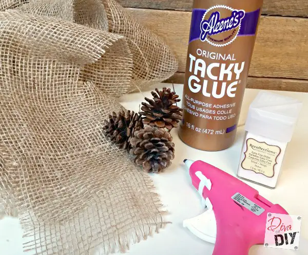 A bottle of tacky glue and pine cones on a table. How To Make Burlap Flowers.