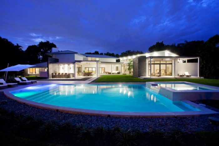 A contemporary house with a nighttime swimming pool.