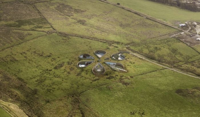 An aerial view of an underground circular building in the middle of a field.