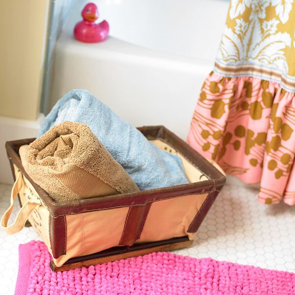 A basket filled with towels and a pink rug in a bathroom, providing storage for bathroom towels.