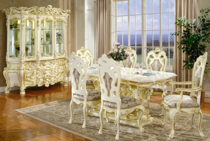 An ornate Victorian dining room with a white table and chairs.