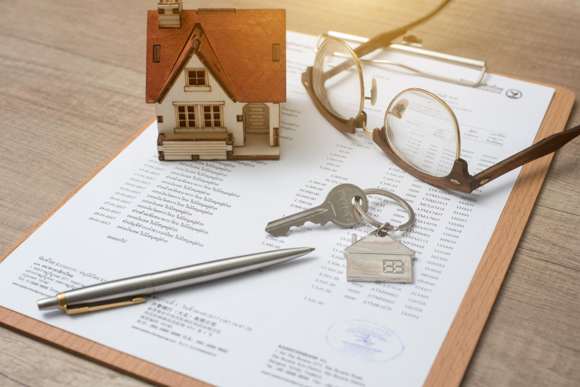 A house model and a mortgage document on a wooden table.