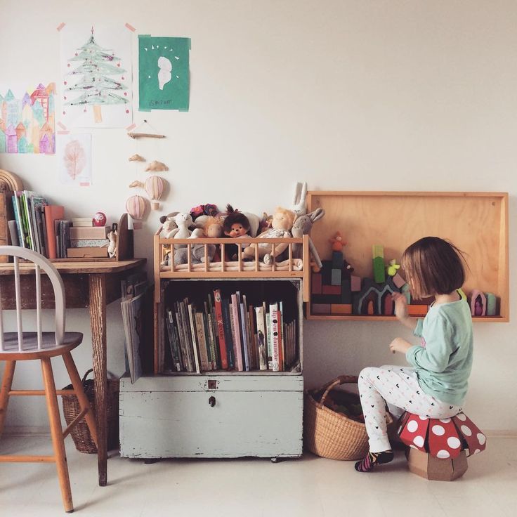 A toddler-friendly playroom with a little girl on a stool.