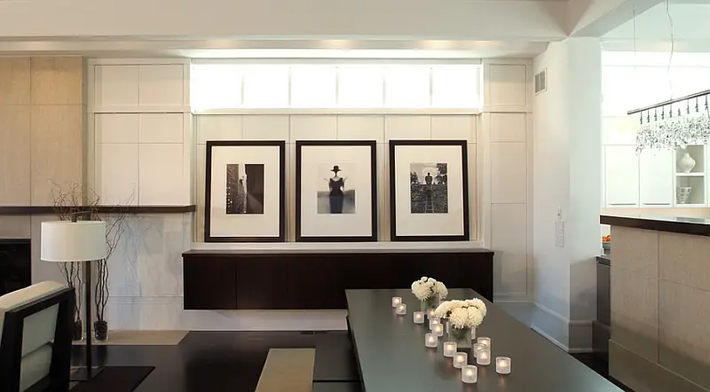 A minimalist dining room with a table and chairs decorated with framed pictures.