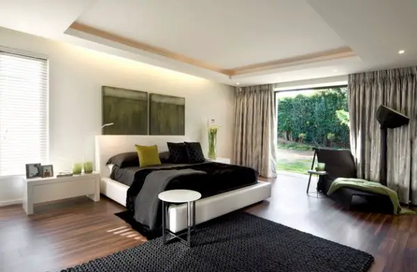 A modern bachelor pad bedroom with a black bed and green accents.