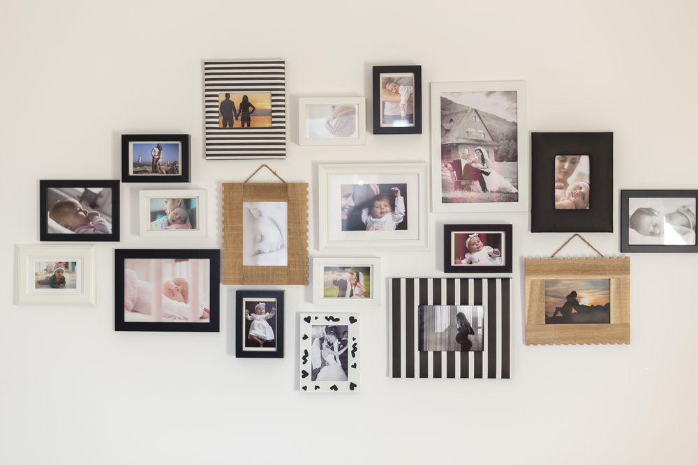 A wall full of black and white framed pictures showcasing updated family photos.
