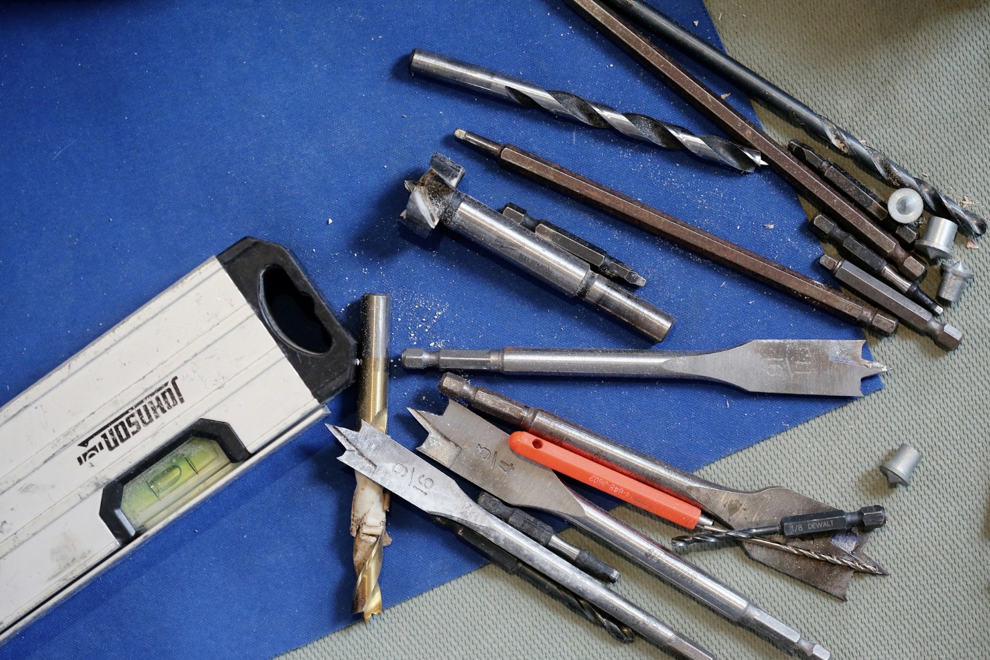 A variety of power tools are laid out on a blue surface.