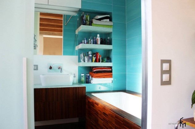 A bathroom with a blue tiled wall and ample storage space.