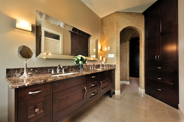 A bathroom with brown cabinets and marble counter tops featuring stylish mirror ideas.