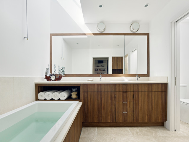 A modern bathroom with wooden cabinets and a large tub featuring stylish bathroom mirror ideas.