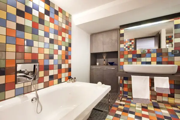 A colorful and tiled basement bathroom with a tub and sink.