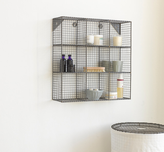 A bathroom with wire storage space for towels on a wall.