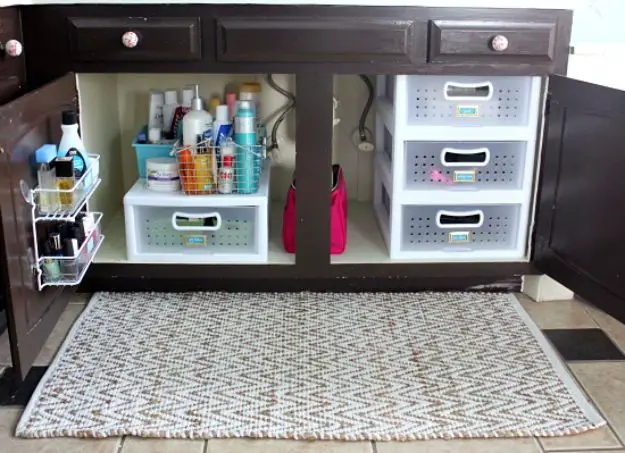 A bathroom storage space with baskets and a rug.