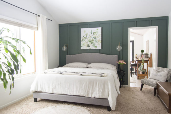A small bedroom with green walls and a white bed.
