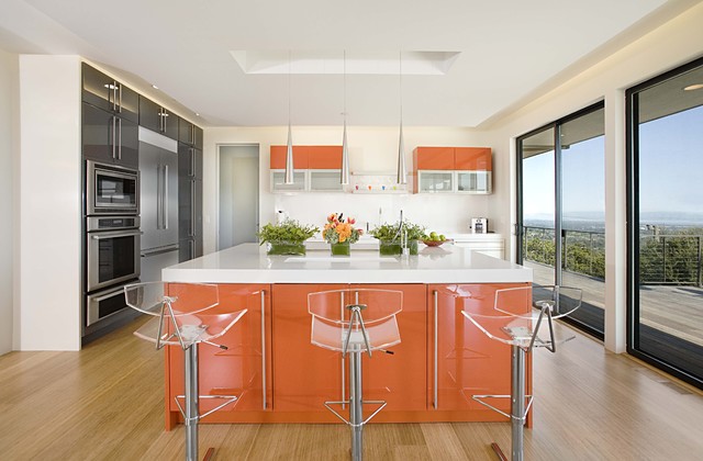 A modern kitchen with orange cabinets and stools, featuring Kitchen Island Ideas.
