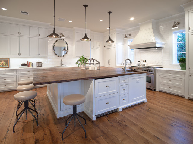 A white kitchen with a centered island and stools, providing kitchen island ideas.