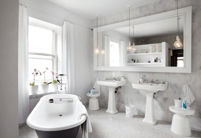 A white bathroom with two sinks and a bathtub, featuring stylish bathroom mirror ideas.