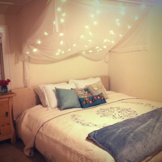 A bedroom with string lights hanging over a bed.