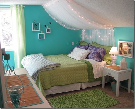 A girl's bedroom with a green and blue color scheme decorated with string lights.