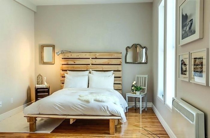 A small bedroom with wooden floors and a bed made out of pallets.