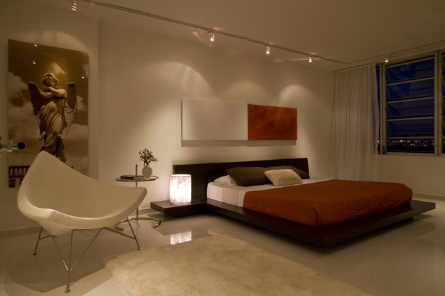 A modern bedroom with white walls and a white bed showcasing minimalistic decoration.
