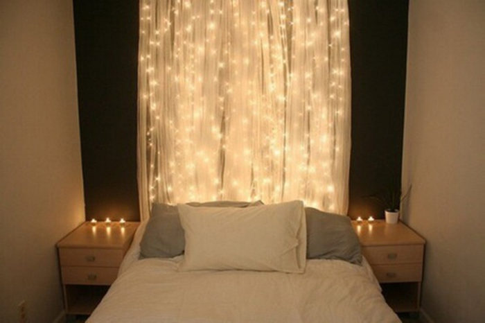 A bedroom with white sheets and string lights.