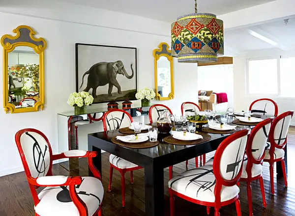 A dining room with red and white chairs and a mirror, featuring a table.