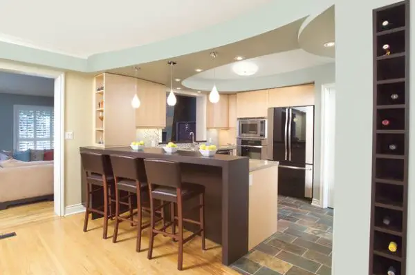 A kitchen with a high dining room ceiling, bar stools, and a wine cellar.
