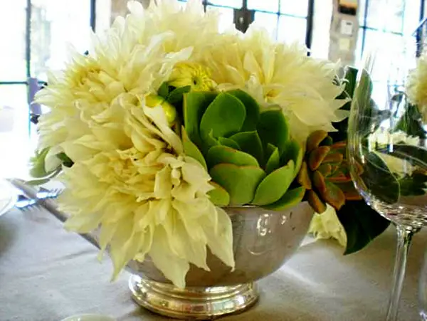 A white flower centerpiece on a dining room table.