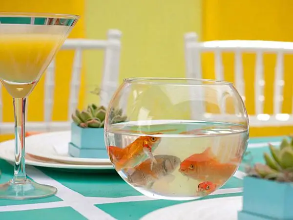 A dining room table centerpiece featuring a goldfish bowl and a martini.