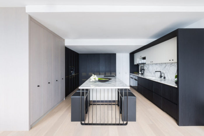 A kitchen with black and white cabinets and wooden floors.
