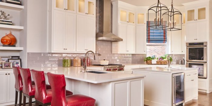 A white kitchen with red chairs and a center island, showcasing kitchen cabinet makeover ideas.