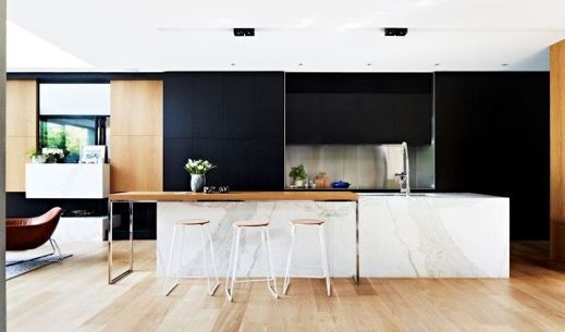 A modern black and white kitchen with wooden floors.