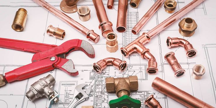 A group of plumbing tools on top of a blueprint illustrating what to look for in a plumbing professional.