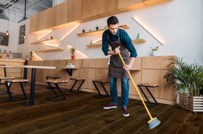 A man cleaning the flooring in a restaurant's dining room.