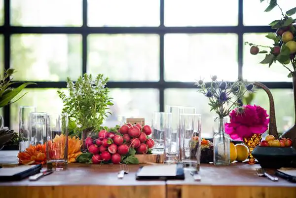 A dining room table centerpiece adorned with flowers and fruit.