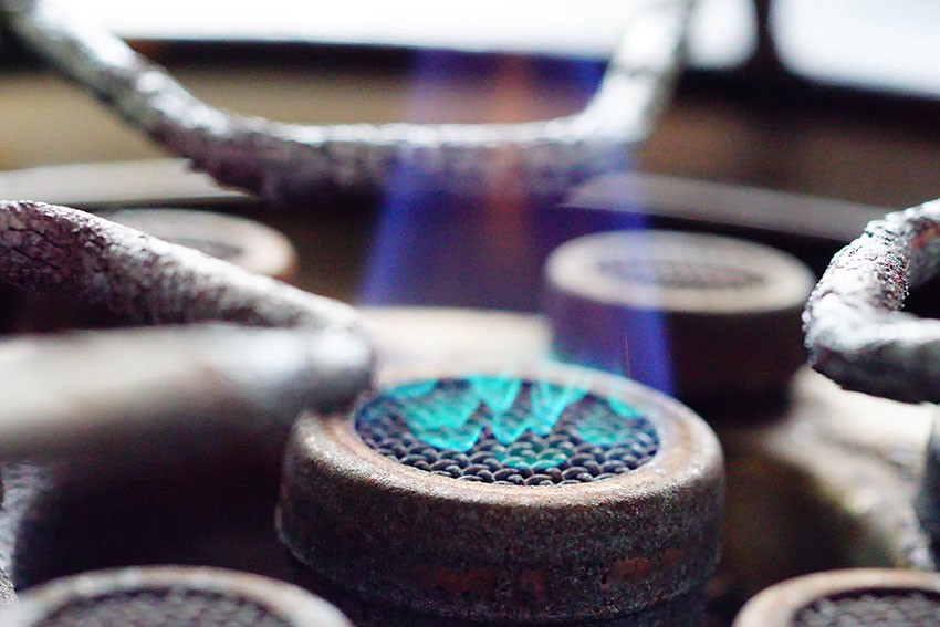 A close up of a gas stove with blue flames for kerosene home heating.