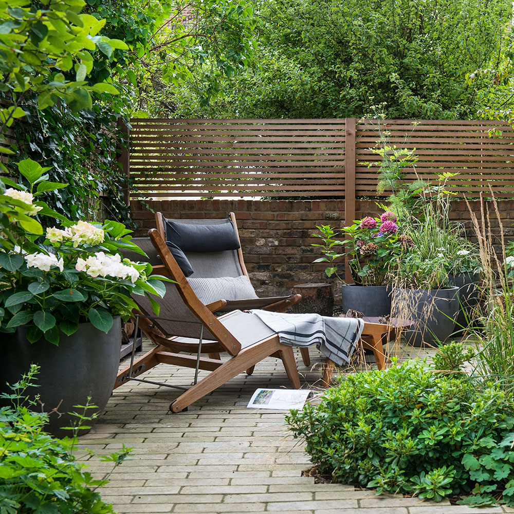 Designing a cozy garden retreat with wooden fence and comfortable chairs.