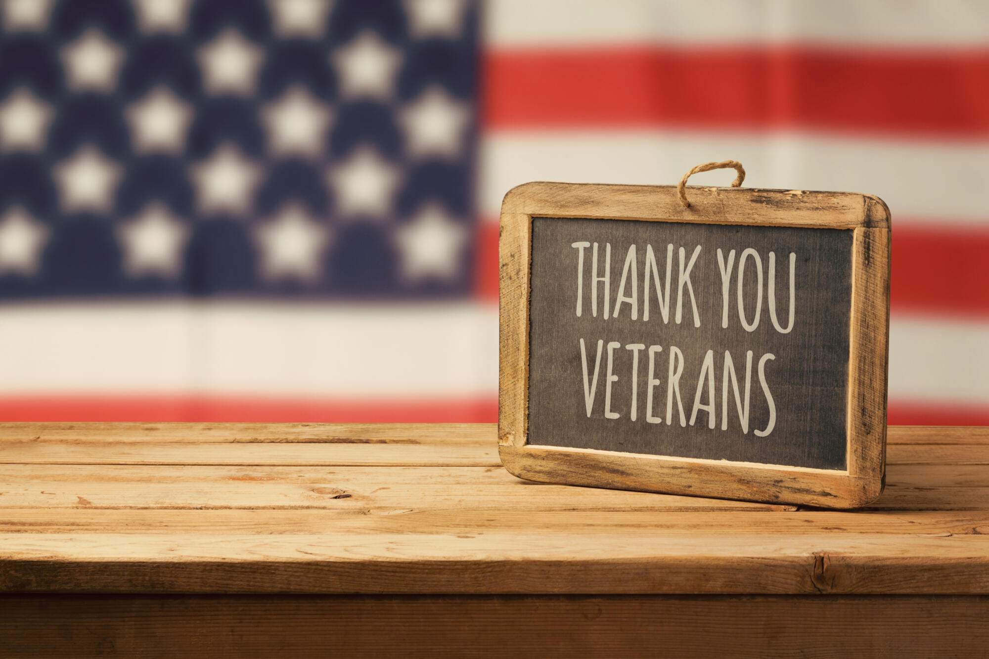 A wooden board featuring a patriotic American flag and the heartfelt words "thank you" to veterans.