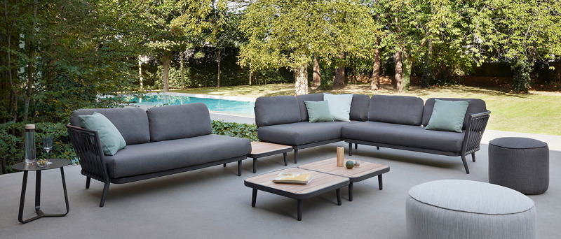A grey sectional outdoor furniture set on a patio next to a pool.