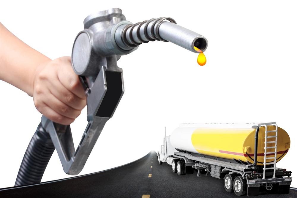 A person pouring heating oil into a truck on a highway.