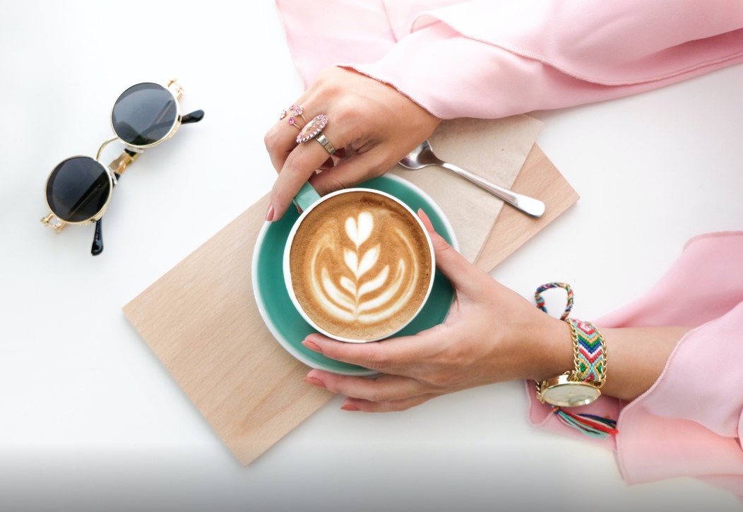 A woman's hand holding a luxurious cup of coffee.