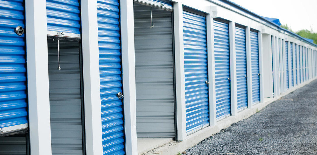A row of blue storage units in a parking lot for business alternatives to office space.