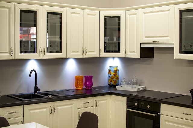 A kitchen with white cabinets and black counter tops available for buying kitchen cabinets online.